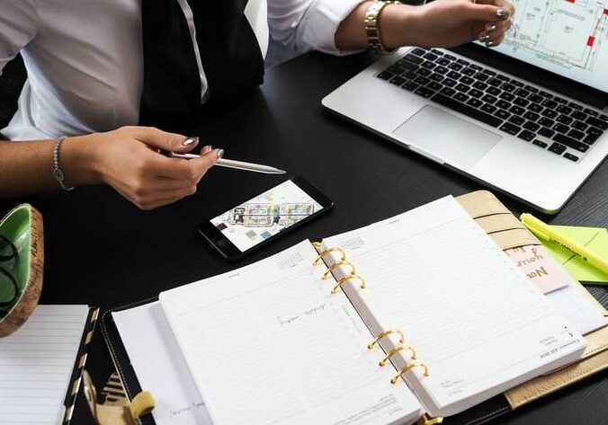 Two people sitting at a table with papers and laptops.